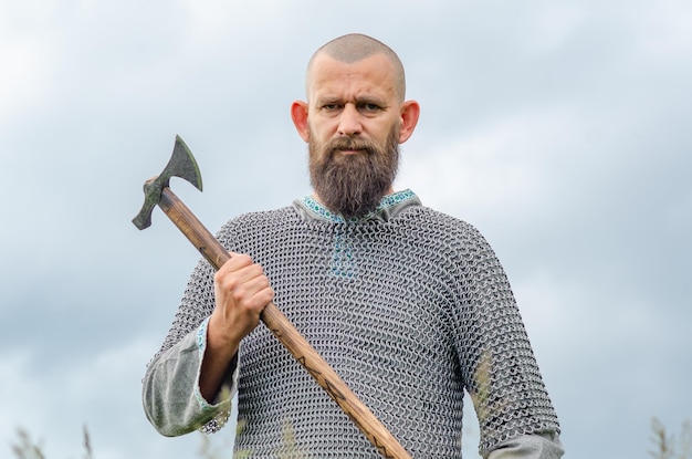 Una emotiva foto de un vikingo medieval en una cota de malla metálica blandiendo un hacha