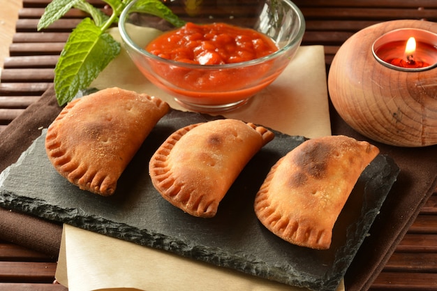 Empanada de atún hecha en casa con salsa de tomate en mesa de madera