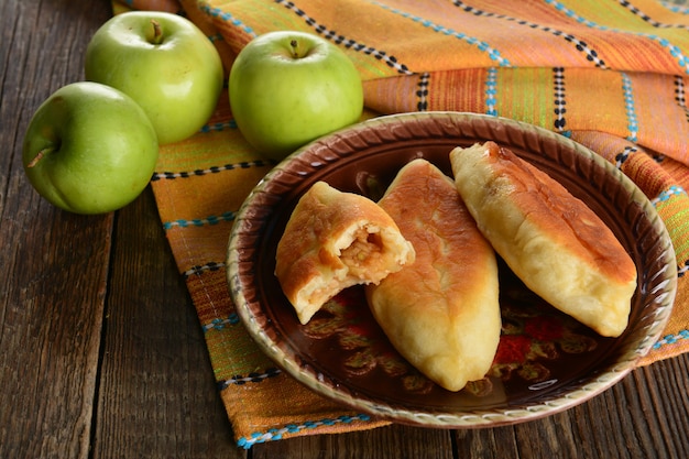 Empanada caliente con manzanas verdes frescas sobre fondo de madera