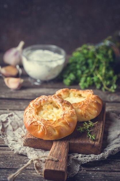 Empanadas abiertas caseras frescas con queso. Pastelería de levadura tradicional rusa, bollos redondos, tarta de cuajada. Bollos con requesón. Estilo rústico. Fondo de madera