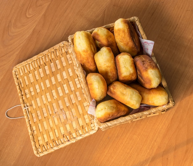 Empanadas al horno caseras tradicionales o empanadas con mermelada en una cesta de mimbre. Pirozhki ruso frito hecho de masa de levadura en estilo rústico