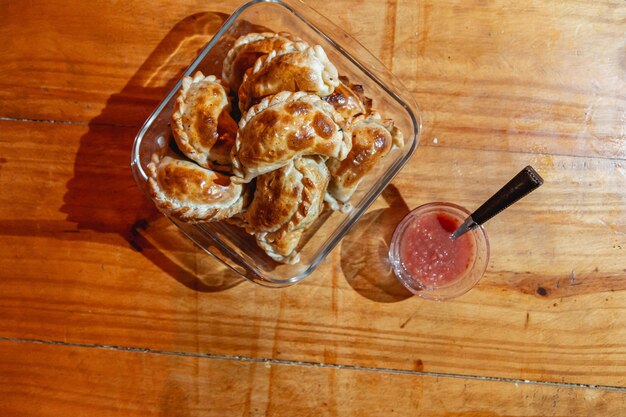 Empanadas al horno sobre una mesa de madera con salsa picante