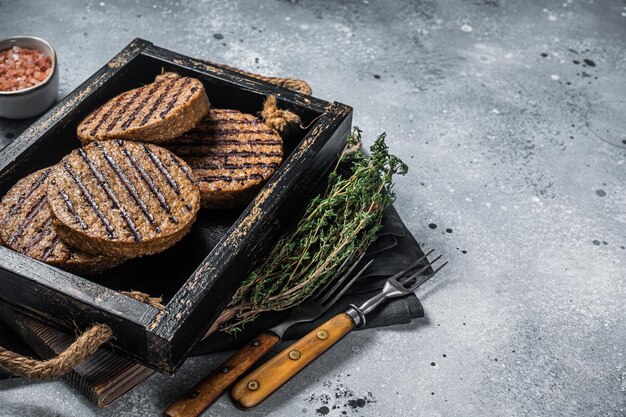 Empanadas sin carne asada chuletas de hamburguesa de carne a base de plantas en bandeja de madera con hierbas Fondo gris Vista superior Espacio de copia