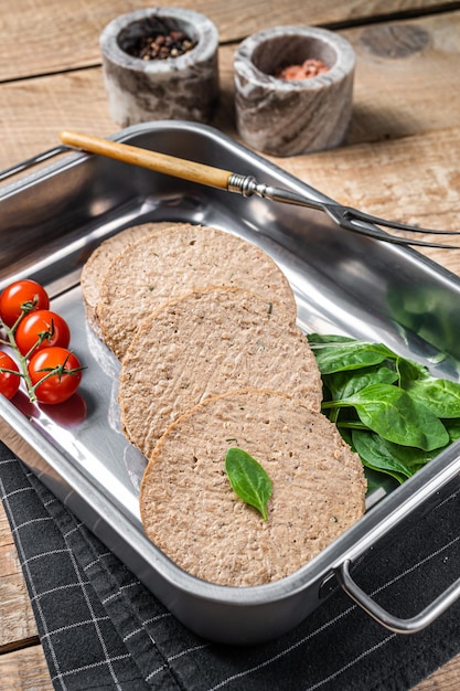 Empanadas sin carne cruda hechas de carne a base de plantas chuletas de hamburguesas veganas frescas en bandeja de cocina con hierbas Fondo de madera Vista superior