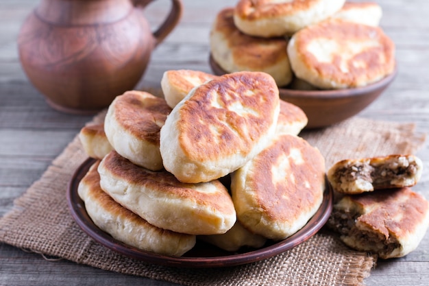 Empanadas fritas con la carne en el plato sobre fondo de madera vieja