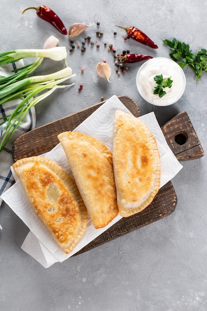 Foto empanadas fritas caseras con carne de cerdo, chebureks con carne picada sobre una tabla de madera