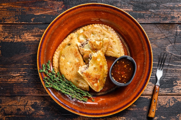 Empanadas fritas com carne picada de carne bovina servidas em prato com molho de pimenta
