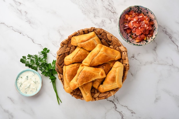 Empanadas fritas com coentro, carne, ovo, tomate e molho de pimenta no fundo branco. conceito de dia da independência da américa latina e do chile.