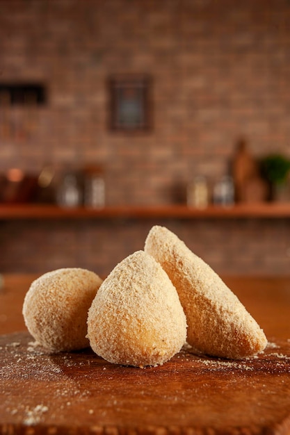 Foto empanado de croquetas brasileñas coxinha de frango risolis de carne e bolinha de queijo sobre fondo de pared de ladrillos de cocina