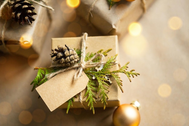 Empaque un regalo para Navidad y año nuevo en materiales ecológicos: papel kraft, ramas de abeto vivo, conos, cordel. Etiquetas con mock up, decoración natural, hechas a mano, bricolaje. Actitud festiva. Fondo de navidad