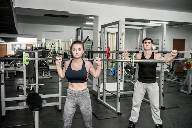 Emparelhe o instrutor de treinamento com a mulher, ambas segurando halteres