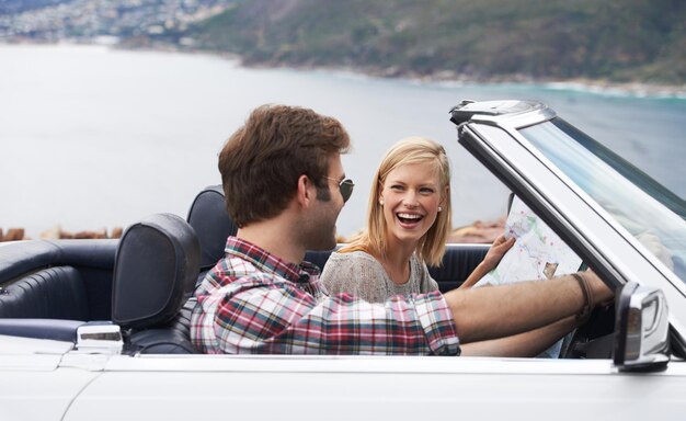 Empecemos a conducir Foto de una pareja joven disfrutando de un paseo por la costa en un descapotable