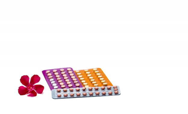 Empfängnisverhütende Pillen oder Antibabypillen mit der rosa Blume lokalisiert auf weißem Hintergrund. Hormon zur Empfängnisverhütung. Familienplanung Konzept. Runde Hormontabletten in Blisterverpackung. Hormonelle Akne.