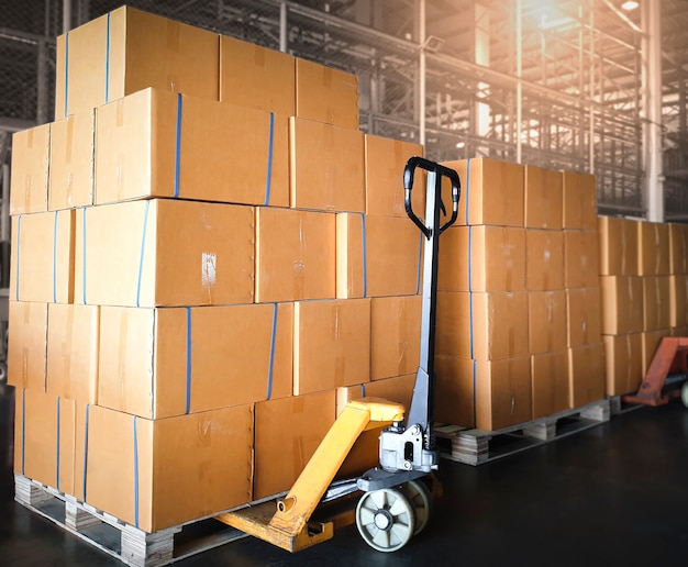Empilhados de caixas de pacotes com paleteira manual no armazém de armazenamento Logística do armazém de envio