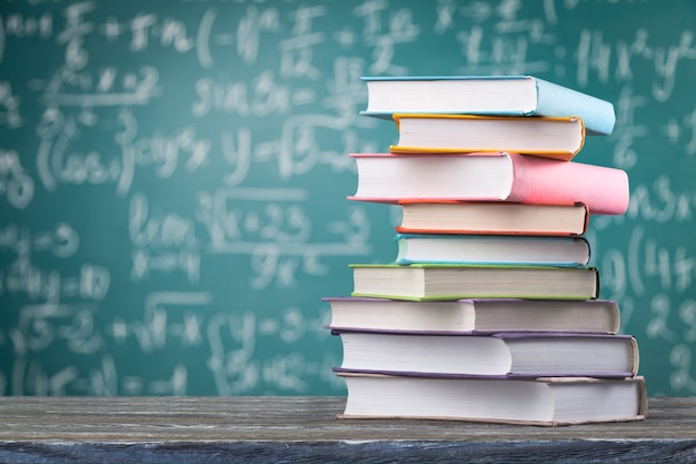 Foto empilhamento de livros. é um livro aberto, livros de capa dura na mesa de madeira e fundo azul. de volta à escola.