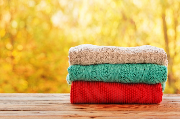 Empilhe a pilha da roupa feita malha do outono na natureza ao ar livre.