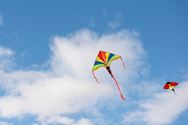 Empinando pipa uma pipa multicolorida está voando no céu azul com nuvens e espaço de sol para texto ou ...