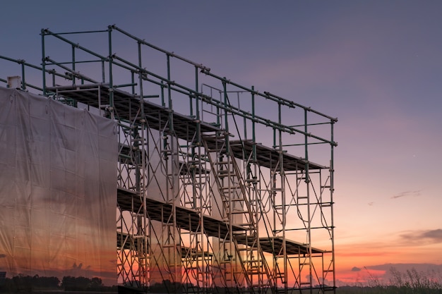 Emplazamiento de la obra con la torre del andamio y edificio con el fondo de la puesta del sol