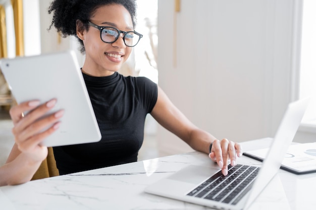 Una empleada que trabaja en una oficina usa una computadora portátil para escribir una respuesta a un cliente