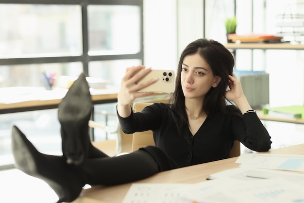 Empleada relajada se toma selfie en el teléfono inteligente en el lugar de trabajo mujer morena concentrada