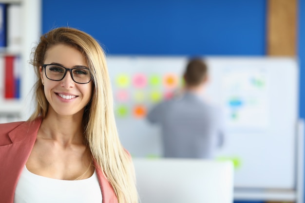 Foto empleada rubia sonriendo en la oficina