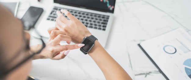 Foto la empleada usa un reloj inteligente en el lugar de trabajo de la oficina