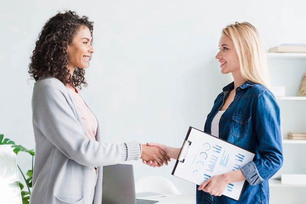 Empleadas multirraciales que dan la mano en la oficina