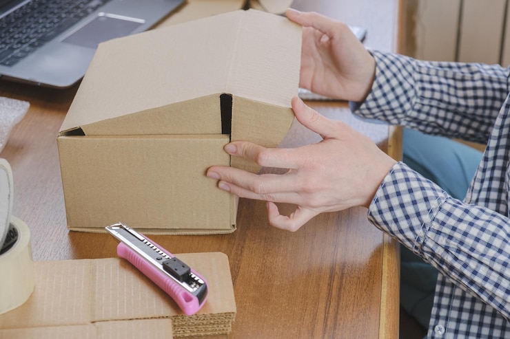 Foto empleado de almacén empaqueta el pedido de la tienda online en una caja de cartón