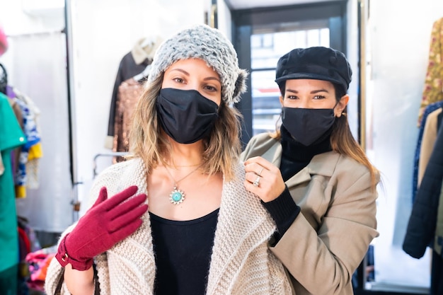Empleado caucásico con máscara de una tienda de ropa probándose a un cliente una joya frente a un espejo, medidas de seguridad en la pandemia de coronavirus, covid-19