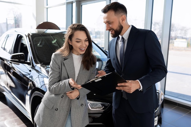 Un empleado de una compañía de seguros ayuda a entender la póliza de seguro de un comprador de un auto nuevo