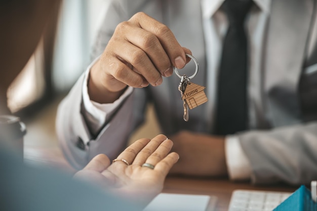 Un empleado de una empresa de alquiler de viviendas entrega las llaves de la casa a un cliente que ha aceptado firmar un contrato de alquiler en el que se explican los detalles y las condiciones del alquiler Ideas de alquiler de viviendas e inmuebles