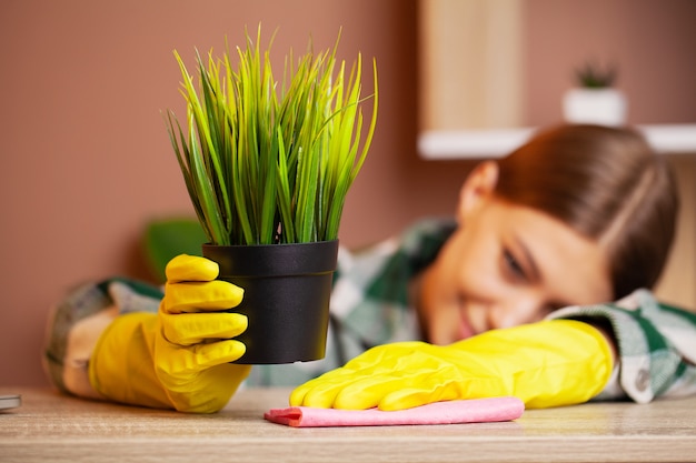 Un empleado de una empresa de limpieza limpia la oficina y cuida las plantas.