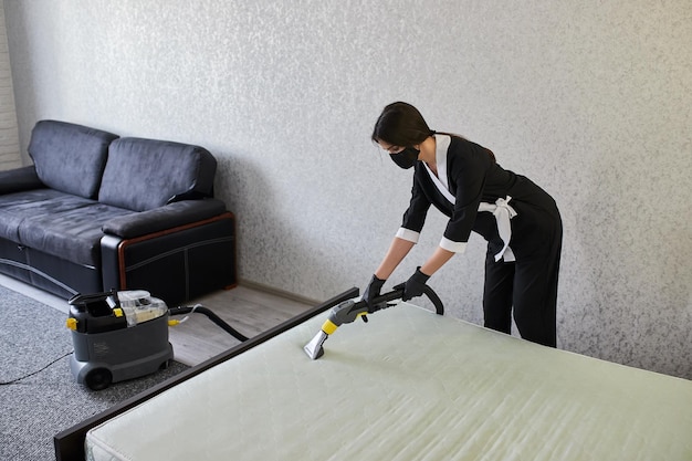 Empleado de la empresa de servicios de limpieza quitando la suciedad de los muebles en un piso con equipo profesional Mujer ama de casa limpiando el colchón en la cama con una aspiradora de lavado