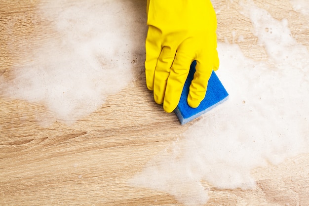 Empleado con esponja para limpiar la mesa de madera