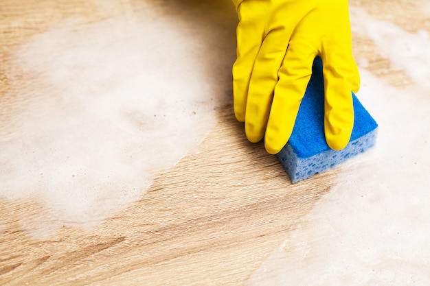 Empleado con esponja para limpiar la mesa de madera