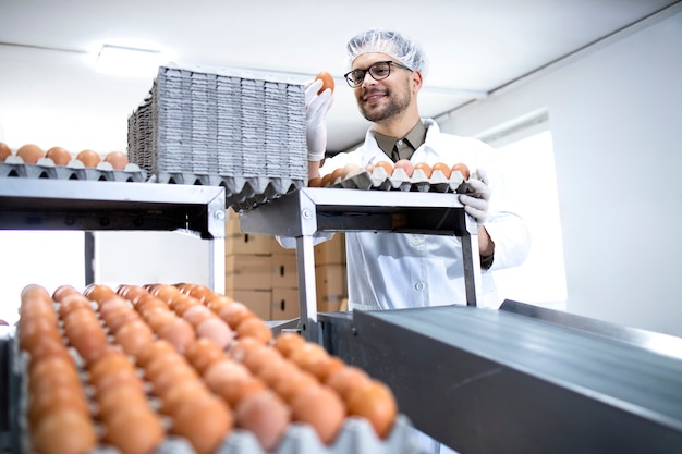 Empleado de fábrica inspeccionando y verificando la calidad de un huevo en la planta de procesamiento de alimentos.