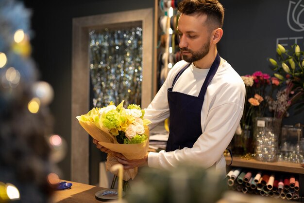 Un empleado de una floristería con un ramo en las manos contra el fondo de los estantes con