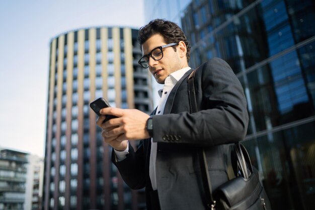 El empleado gerente masculino en una empresa financiera usa un teléfono para ir a la oficina con un traje de negocios