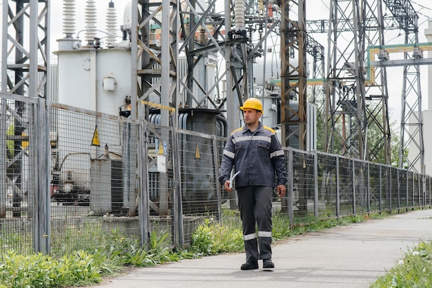 Un empleado de ingeniería hace un recorrido e inspección de una subestación eléctrica moderna. Energía. Industria.