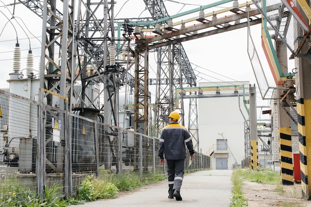 Un empleado de ingeniería hace un recorrido e inspección de una subestación eléctrica moderna. Energía. Industria.