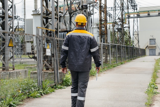 Un empleado de ingeniería realiza un recorrido e inspección de una subestación eléctrica moderna.