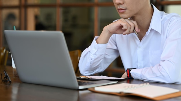 Empleado joven enfocado que analiza datos financieros en una computadora portátil