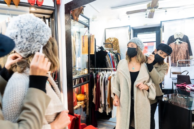 Empleado con máscara en una tienda de ropa probándose una joya a un cliente que trabaja con