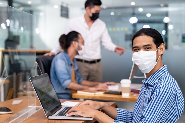Foto empleado de oficina asiática con mascarilla protectora que trabaja en la nueva oficina normal