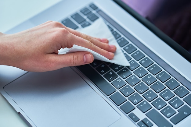 Foto el empleado de oficina desinfecta y limpia el teclado de trabajo con toallitas húmedas antibacterianas para proteger contra el brote de coronavirus.