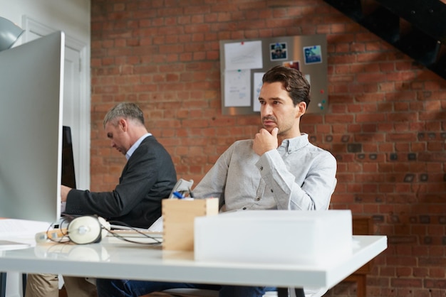 Empleado de oficina de joven empresario en el escritorio y hombre pensando en una solución de negocio de estrategia y una idea de marketing en una agencia de publicidad Empresa de consultoría corporativa Consultor de CRM y profesional de la empresa