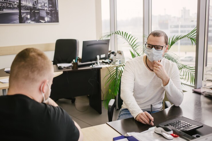 Foto un empleado de oficina con una máscara protectora habla con un cliente