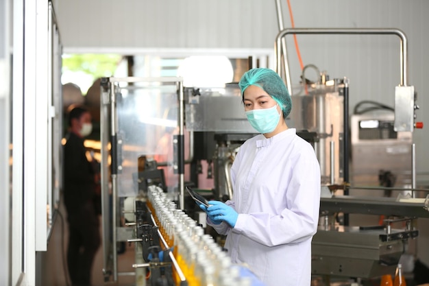 El empleado de producción de bebidas trabaja en la línea de producción de verificación de calidad de fabricación de alimentos y bebidas
