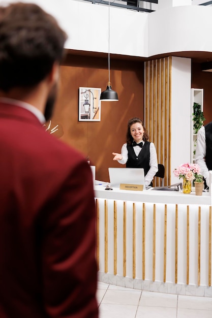 Foto empleado que da la bienvenida al hombre de negocios en el vestíbulo, proporcionando servicios de lujo para los huéspedes que viajan en viaje de trabajo.