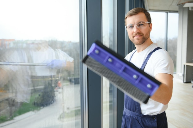 Un empleado de un servicio de limpieza profesional lava el vidrio de las ventanas del edificio Limpieza de vitrinas para tiendas y negocios